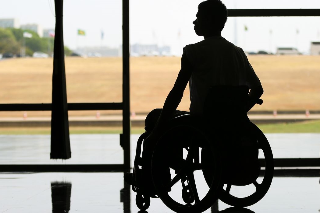Pessoa com deficiência física em cadeira de rodas em sombra